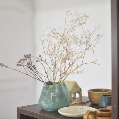 A beautiful, organically shaped vase made by a student, now holding delicate dried flowers. Simple and elegant.