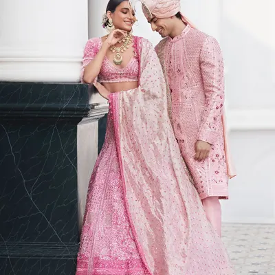 Where every stitch tells a love story. This stunning couple is a vision in coordinated pink outfits, perfect for an engagement or pre-wedding celebration. We design custom couture for your bridal dreams.
