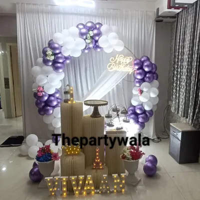 A chic ring decoration with purple and white balloons, a sheer white curtain, and light-up letters for the name 'VIVAAN'.
