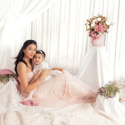 A dreamy mother-daughter portrait in our light and airy studio setup. The soft fabrics and floral arrangements create a beautiful, ethereal feel.