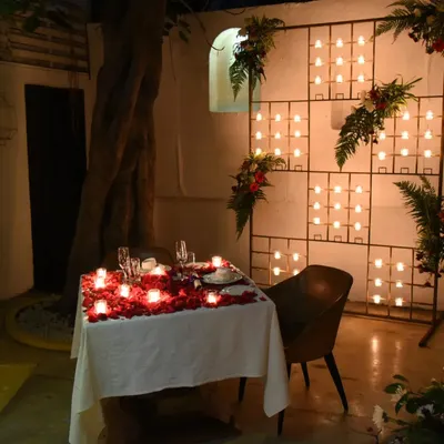 A table for two, transformed into a canvas of romance with scattered rose petals and a wall of candles, perfect for a proposal or anniversary.