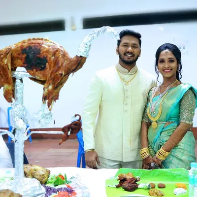 A happy couple posing with our signature Raja Virundhu, a whole roasted mutton presented in a celebratory style. It's more than a dish; it's a centerpiece for your feast.