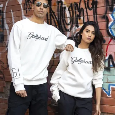 A duo shot for a streetwear brand, featuring matching sweatshirts against a graffiti wall. This image establishes a cool, urban aesthetic and is great for showing unisex apparel.