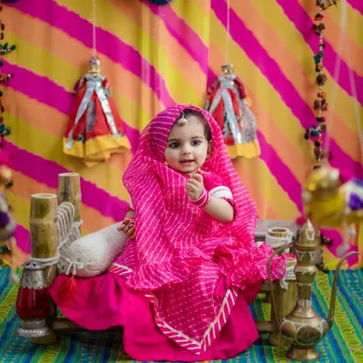 A little Rajasthani princess in a vibrant pink leheriya outfit. We created this entire set to celebrate her milestone with cultural richness and bright, joyful colors.