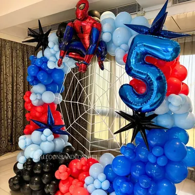 An action-packed Spider-Man setup for a 5th birthday. The circular balloon arch in red, blue, and black perfectly frames the web backdrop, with the hero himself ready for action.