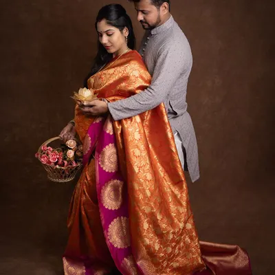 A beautiful moment from a traditional maternity shoot. The rich silk saree, the basket of flowers, and the gentle way he holds her create a picture of timeless love.