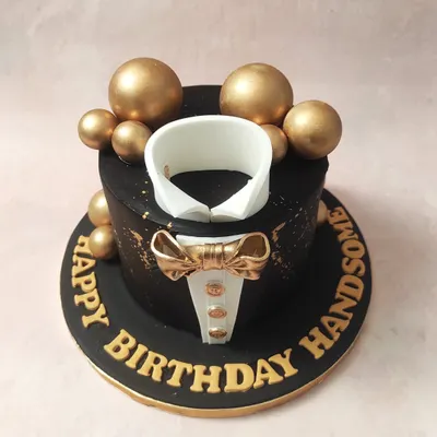An overhead view of our black and gold Tuxedo Cake, showing the crisp white collar surrounded by shimmering gold spheres.