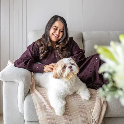 A beautiful, relaxed portrait of Shruti and her Shih Tzu, Kyro, cuddling on the couch. At-home sessions allow for this kind of natural comfort and genuine connection.