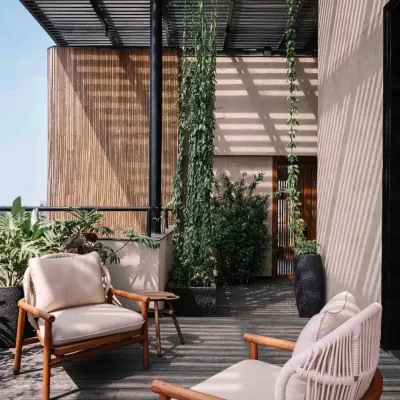 A cozy seating area on a wooden deck at Project 1374. The space is sheltered by a pergola and surrounded by vertical gardens, creating a private oasis that feels both indoors and outdoors.