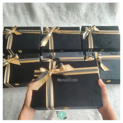 A fleet of elegant black suede boxes ready for a corporate order. Each box is tied with a gold and black ribbon, ready to be filled with curated items that show genuine employee appreciation.
