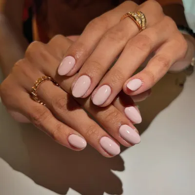 A perfect example of timeless elegance. This manicure features a classic, clean nude-pink polish on beautifully shaped short, oval nails for a look that is effortlessly chic and sophisticated.