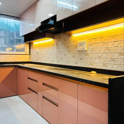 A modern L-shaped kitchen with glossy pink base cabinets and white overhead units. The geometric backsplash tiles and under-cabinet lighting create a bright and inviting cooking space.
