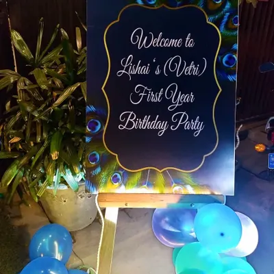 Welcome your guests in style with a custom-designed welcome board. This one was created for a peacock-themed party, featuring elegant script and a beautiful feather design.