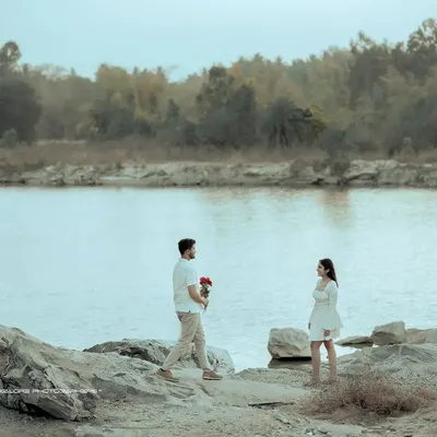 A classic romantic gesture. The groom approaches with flowers against a vast, tranquil lake, creating a scene straight out of a storybook for this pre-wedding shoot.