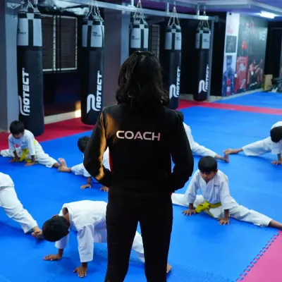 Expert guidance is at the heart of our dojo. A dedicated coach leads a class of young karate students through their warm-up stretches, ensuring proper form and instilling discipline from the very start of their martial arts journey.