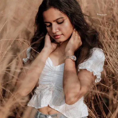 A soft, naturally lit portrait in a field of tall grass. The warm tones and the model's gentle expression create a serene and beautiful image.