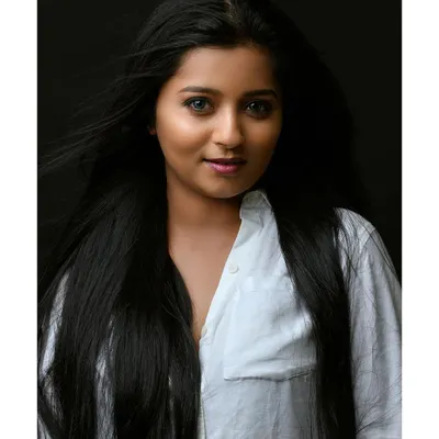 A simple and beautiful headshot with a clean, dark background. The wind in her hair adds a dynamic element, while her direct gaze creates a strong connection with the viewer.