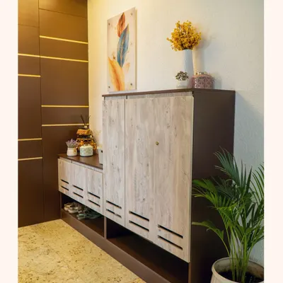 A welcoming and organized entryway is essential. I designed this custom foyer unit with a ventilated shoe rack in a light wood finish and a taller dark wood cabinet to conceal utility panels, creating a clean and stylish first impression.
