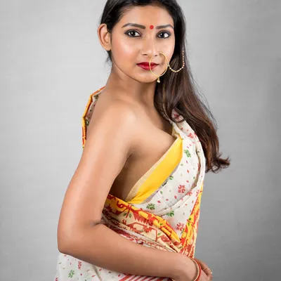 A classic Bengali saree look, captured with a direct and expressive gaze. The focus here is on the subtle power and beauty of traditional attire, highlighting the intricate details of the fabric and the model's confidence.
