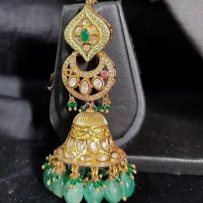 A magnificent pair of chandbali jhumkas with green enamel work and cascading green beads. These rental earrings are perfect for making a grand statement.