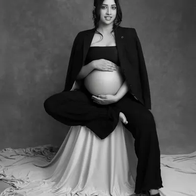 A powerful and confident solo maternity pose. The mom-to-be's seated pose, combined with the chic blazer and black and white finish, creates a modern and artistic portrait.