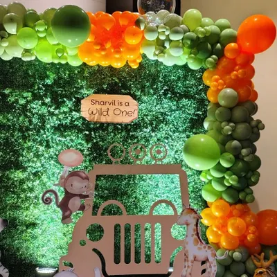A closer look at our "Wild One" jungle safari theme. This setup features a lush greenery wall backdrop, a custom jeep cutout for photos, and an organic balloon garland in jungle-inspired shades of green and orange, perfect for a first birthday.
