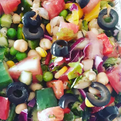 A colourful and high-protein Mediterranean salad. It's packed with chickpeas, fresh vegetables like cucumber and tomatoes, and black olives, all tossed in a light, zesty dressing.