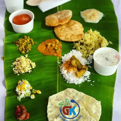 A Complete Vegetarian Meal: A perfectly balanced South Indian meal served on a banana leaf. It includes rice, sambar, poori, kosambari, palya, pickle, sweet pongal, and a gulab jamun.