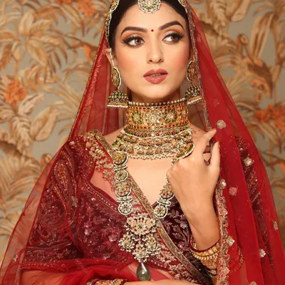 A regal and timeless bridal portrait. This look features a deep red velvet lehenga, complemented by makeup that emphasizes sharp, defined eyes and a perfectly sculpted face, fit for a modern queen.