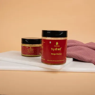 Two jars of Mango Chutney styled on a white marble slab with a pink cloth, creating a clean and appetizing look.