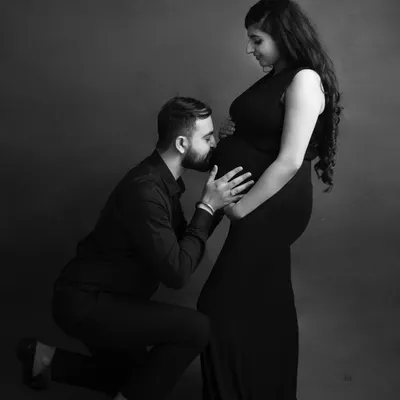A classic and intimate black and white portrait of a partner kissing the baby bump. This pose is a timeless expression of love and anticipation.