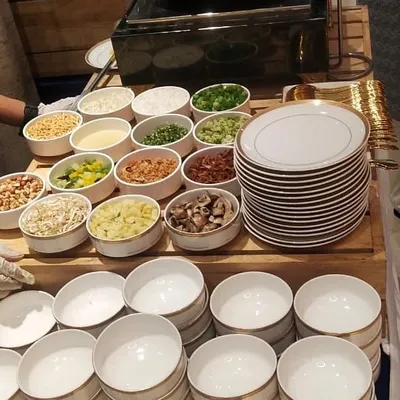 Here is a close look at the wide array of fresh toppings for a Khao Suey station. I provide everything from chopped mushrooms and bean sprouts to fried onions and peanuts, all neatly arranged in clean, separate bowls for easy access.