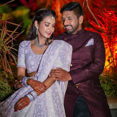 A lovely portrait of a couple during their Sangeet. The bride's lavender lehenga and the groom's deep wine sherwani complement each other perfectly, capturing their elegant style.