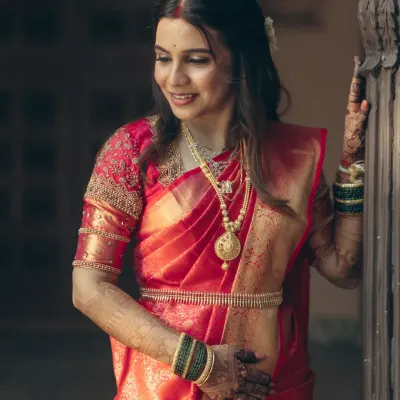 The beautiful bride Madhavi in her red silk saree. Her look features soft, defined eyes and a radiant base, perfect for her wedding ceremony.