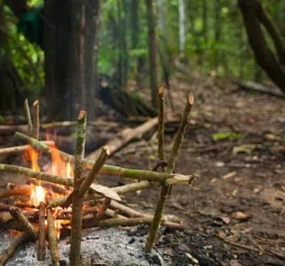 A well-built campfire is a survivor's best friend. This image shows a cooking and warmth setup created using techniques we teach in our fire-making workshop.