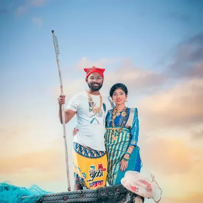 This is a classic Agri-Koli themed portrait. The couple stands in a boat, with the groom holding a traditional paddle, dressed in a lungi and Koli cap. It’s a powerful image that celebrates their cultural roots.