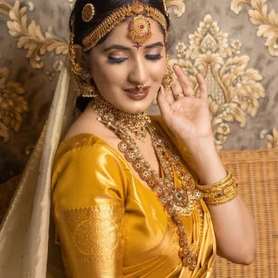 A student's portfolio work featuring a classic South Indian bridal look with a golden silk saree and temple jewellery. The focus here is on creating a radiant, long-lasting base.