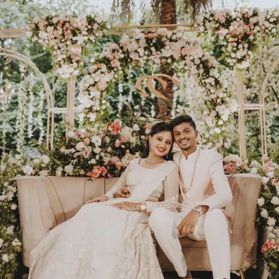 A beautiful portrait of the newly engaged couple, seated against a stunning floral arch at their Roka ceremony.