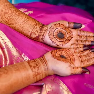 A beautiful bridal mehendi for Anushiya, set against her vibrant pink saree. The design features bold mandalas on the palm and detailed cuff work on the arms, showing how the henna complements the entire bridal look.
