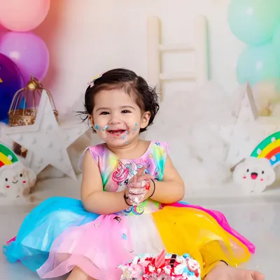 This rainbow-themed cake smash is pure happiness. The colorful dress, matching balloons, and of course, the messy cake, create a perfect first birthday portrait.