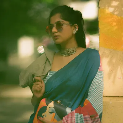 An edgy, modern look featuring a multi-colored patchwork saree. Paired with sunglasses and a quirky clutch, this shot against a graffiti wall shows a different side of saree styling.