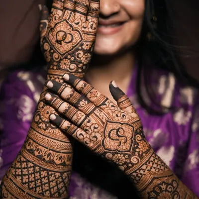 A classic engagement mehndi, beautifully captured to highlight the intricate details. The design features the couple's initials and intertwined rings, symbolizing their union.