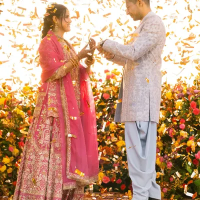 The moment of the ring exchange, showered in golden confetti and sunlight. This is pure joy and celebration, a perfect capture of their engagement.