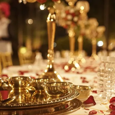 The details matter. This close-up shows the elegant brass thali and bowls I use for my Royal Thali service, set on a beautifully decorated table with flower petals.