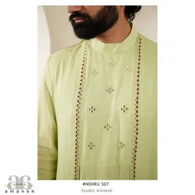 A close-up of the light green kurta, showing the delicate embroidery and mirror work along the placket, worn under our emerald Nehru jacket.