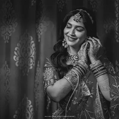 A black and white portrait of the bride adjusting her earring, a smile of anticipation on her face. These quiet, getting-ready moments are filled with emotion.