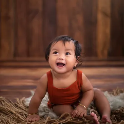 The magic isn't in the props, it's in this smile. A simple wooden backdrop and a soft rug are all that's needed to let this baby's joyful spirit shine through.