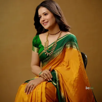 A classic studio portrait that celebrates the beauty of traditional attire. The rich yellow and green silk saree, paired with antique gold jewelry, creates a timeless and graceful look.