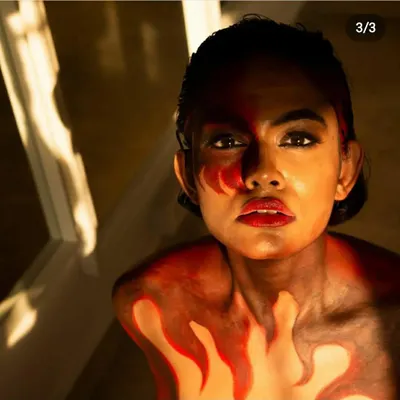 The final look of a fire-themed body painting project. I used a blend of red, orange, and dark tones to create the illusion of flames rising up the model's chest and neck.