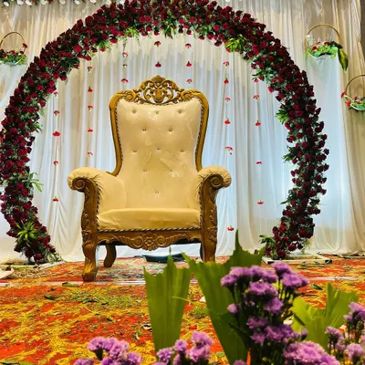 A simple yet elegant floral arch of red roses creates a classic backdrop for a baby shower. The focus remains on the ornate central chair, making the mother-to-be the star of the ceremony.